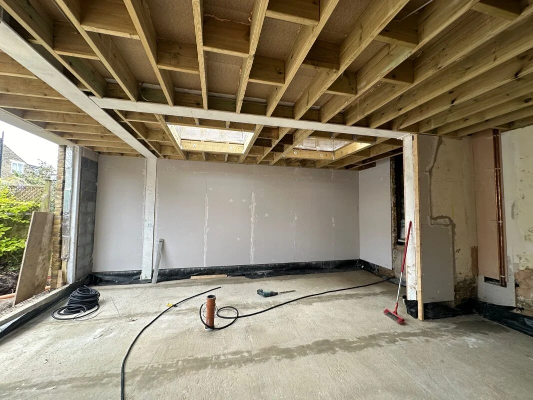 Mid-build view of an extension — timber roof structure, insulation and rooflight openings are where the structural part of the budget goes.